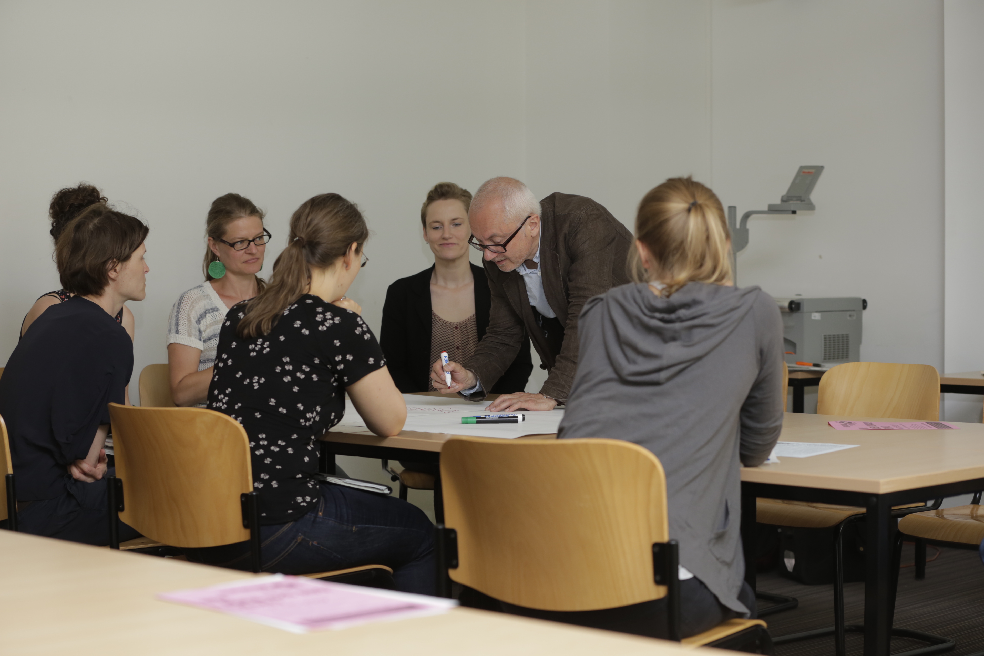 Workshop Teilnehmer*innen sitzen an Tisch und überlegen gemeinsam